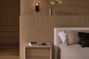 Ložnice s čalouněnou postelí, dřevěným nočním stolkem a jemným osvětlením