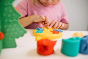 Dítě modeluje barevného dinosaura ze slaného těsta u stolu