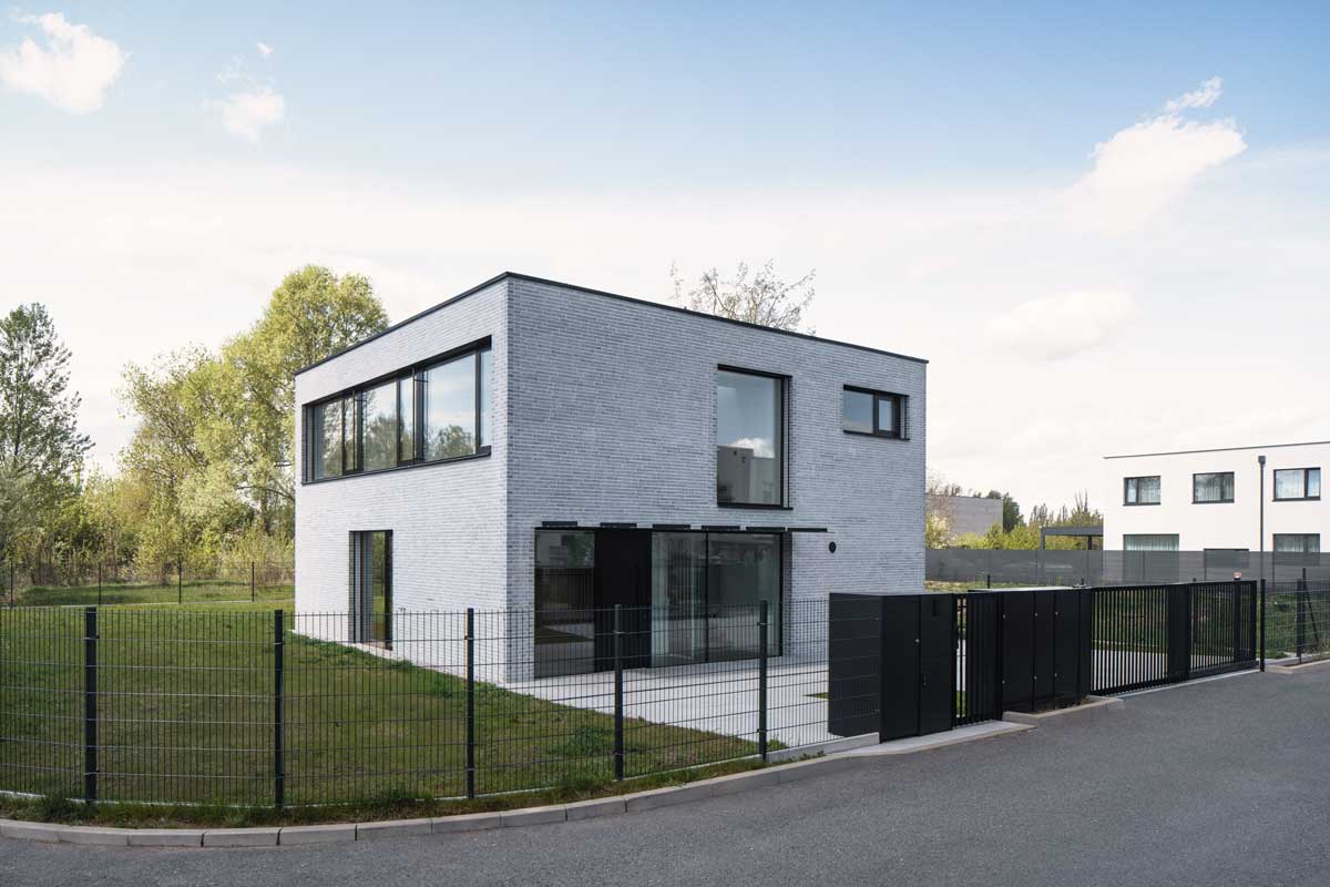 Minimalistický dům s cihlovým obkladem, velkými okny a černými akcenty