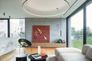 Obývací pokoj s cihlovým obkladem, moderním uměním a velkými prosklenými plochami