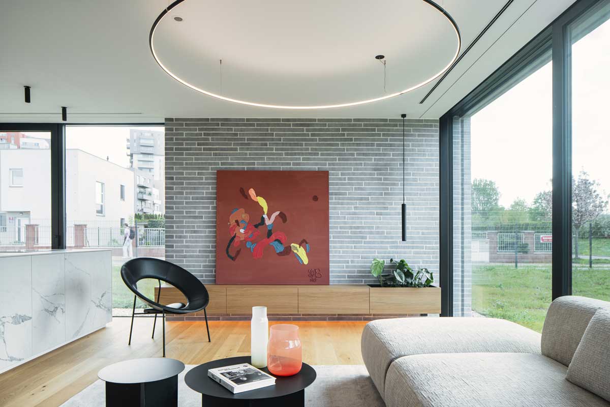 Obývací pokoj s cihlovým obkladem, moderním uměním a velkými prosklenými plochami