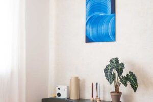 Designová TV skříňka s modrými detaily a výrazným abstraktním obrazem nad ní.