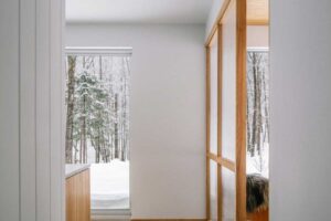 Posuvný panel s dřevěným rámem odděluje klidové místo od kuchyně a propouští světlo.