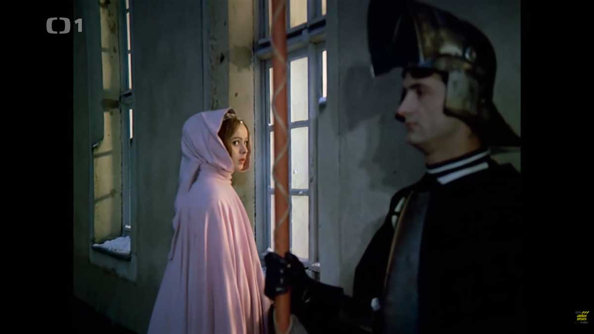 Popelka v růžovém plášti u okna během noční scény ve filmu