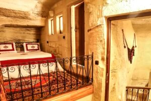 Luxusní ložnice v podzemním domě s ručně tesanými kamennými stěnami a kovovým zábradlím