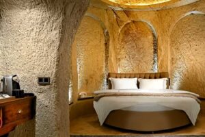 Elegantní ložnice vytesaná do skály s oblouky a kulatým lůžkem