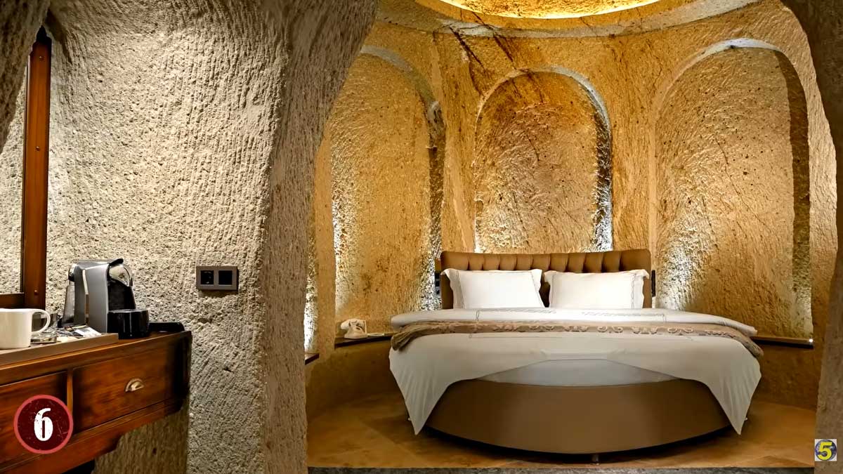 Elegantní ložnice vytesaná do skály s oblouky a kulatým lůžkem