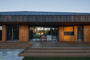 Dřevěná terasa navazující na obytný prostor moderního rodinného domu.