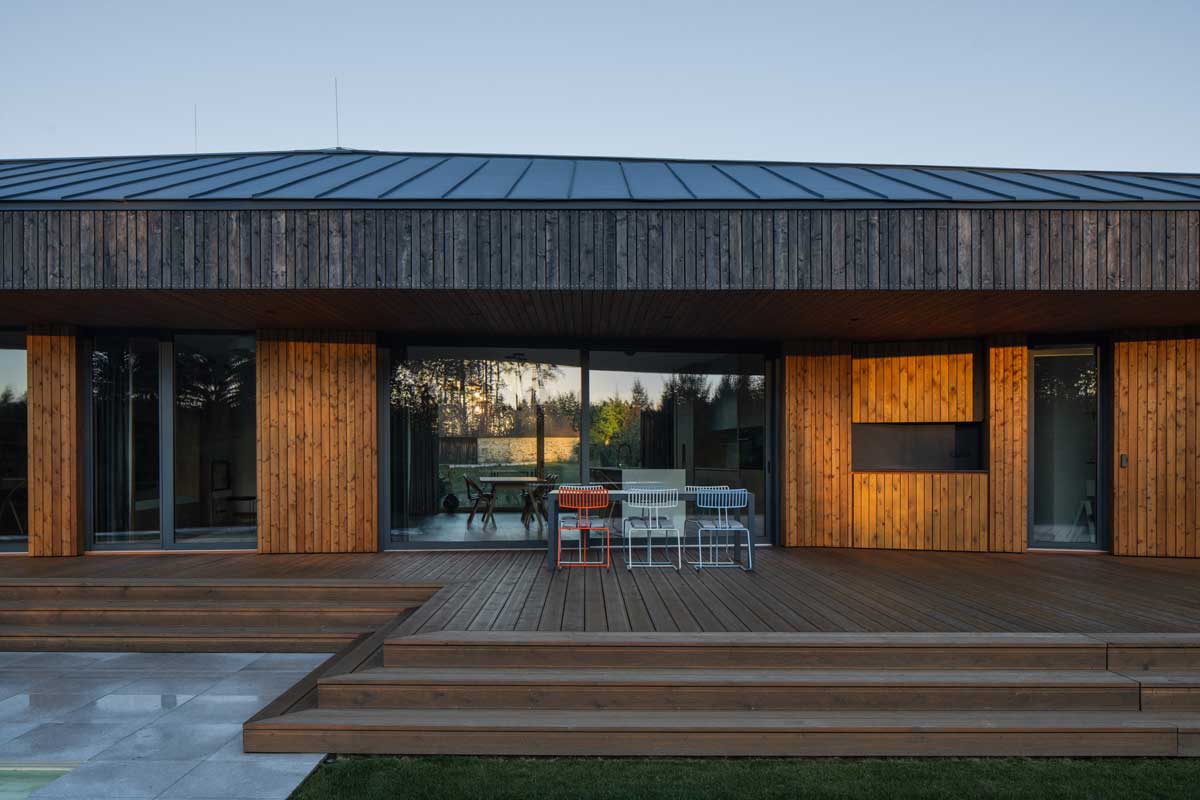 Dřevěná terasa navazující na obytný prostor moderního rodinného domu.