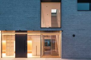 Prosklený vstup rodinného domu s pohledem na plovoucí schodiště a minimalistický interiér