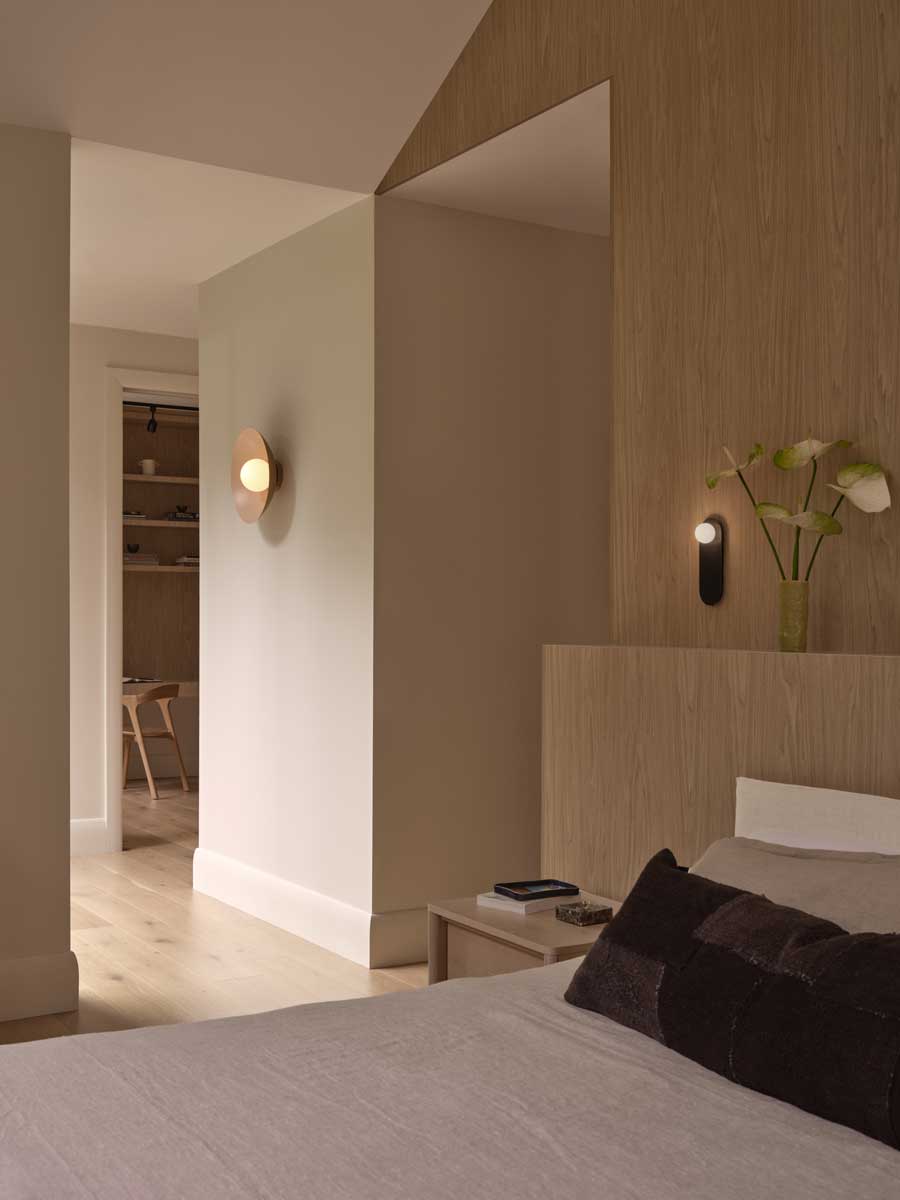 Pohled z ložnice do chodby s dřevěnými obklady a jemným nástěnným osvětlením