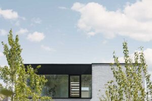 Zadní fasáda domu s velkými okny propojujícími interiér se zahradou