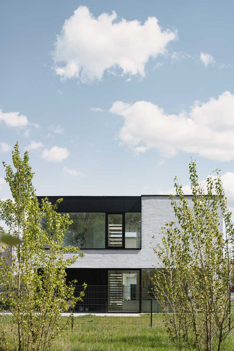 Zadní fasáda domu s velkými okny propojujícími interiér se zahradou