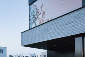 Minimalistická terasa s dvěma zahradními křesly pod přesahem patra