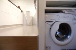 Vestavná pračka ukrytá v boční stěně kuchyně pod vyvýšenou podlahou.