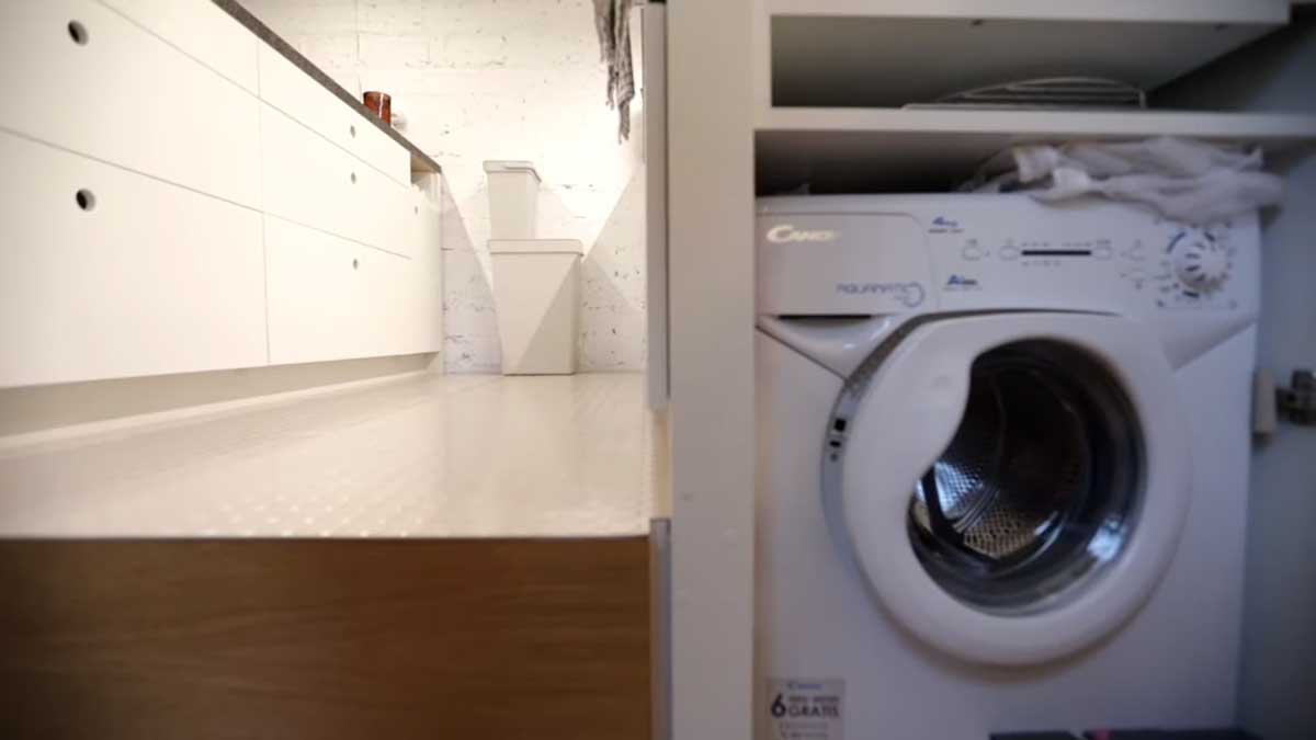 Vestavná pračka ukrytá v boční stěně kuchyně pod vyvýšenou podlahou.