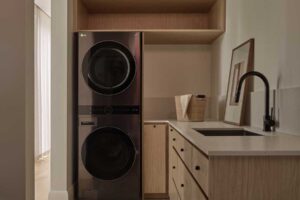 Prádelna s vestavěnými skříněmi, pračkou se sušičkou a dřevěným nábytkem