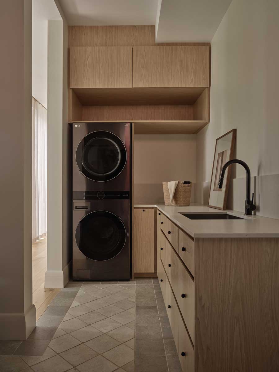 Prádelna s vestavěnými skříněmi, pračkou se sušičkou a dřevěným nábytkem