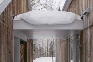 Krytý průchod mezi dvěma objemy domu vytváří klidnou osu, která vede pohledem přímo do zimního lesa.