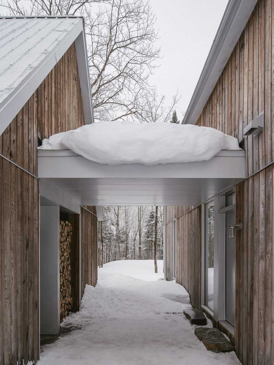 Krytý průchod mezi dvěma objemy domu vytváří klidnou osu, která vede pohledem přímo do zimního lesa.