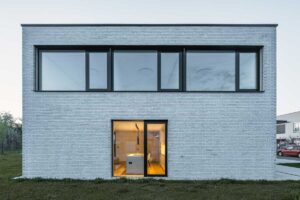 Moderní rodinný dům s cihlovou fasádou a výrazným proskleným vstupem