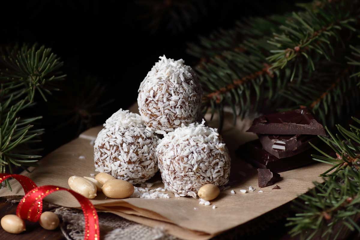 Rumové kuličky obalené v kokosu, naaranžované mezi čokoládou a oříšky v zimní dekoraci.