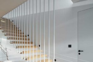 Zavěšené dřevěné schodiště s tenkými bílými pruty jako zábradlím.