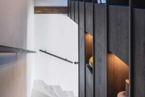 Schodiště s vestavěným úložným prostorem z tmavého dřeva v horské chalupě