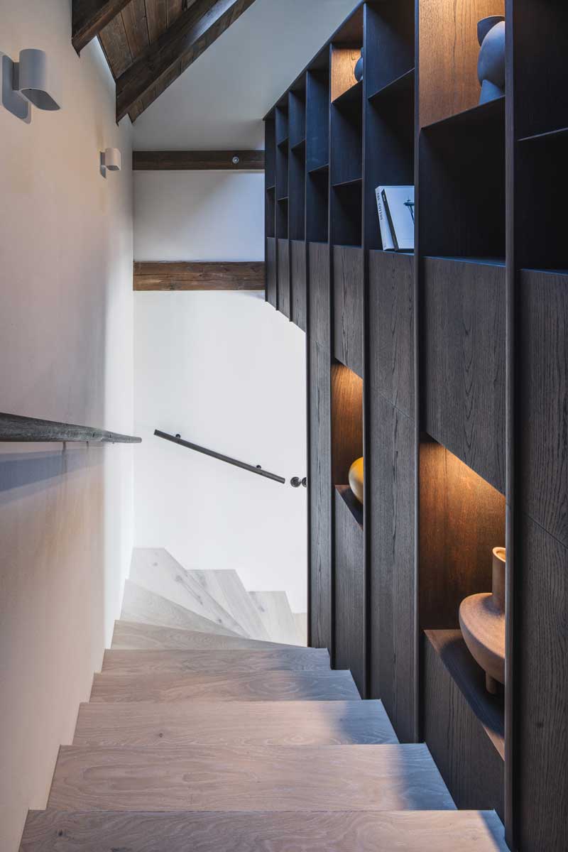 Schodiště s vestavěným úložným prostorem z tmavého dřeva v horské chalupě