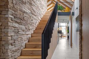 Dřevěné schodiště lemované kamennou stěnou v moderní horské chatě.