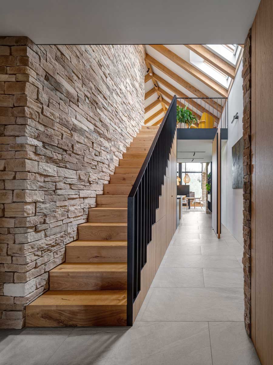 Dřevěné schodiště lemované kamennou stěnou v moderní horské chatě.