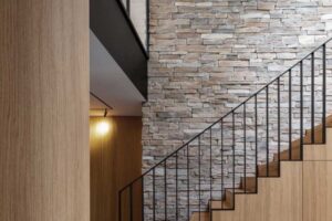 Detail schodiště se zabudovanými úložnými prostory a kamennou stěnou v interiéru.