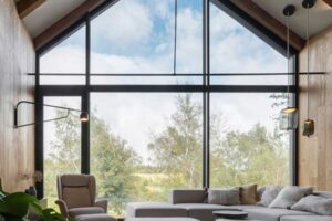 Sedačka orientovaná k velkému prosklenému štítu s výhledem na louky a lesy.