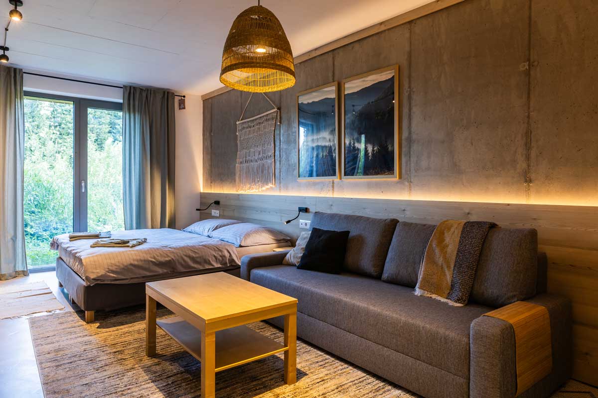 Ložnice se sedačkou a dřevěným obložením v moderní horské chatě