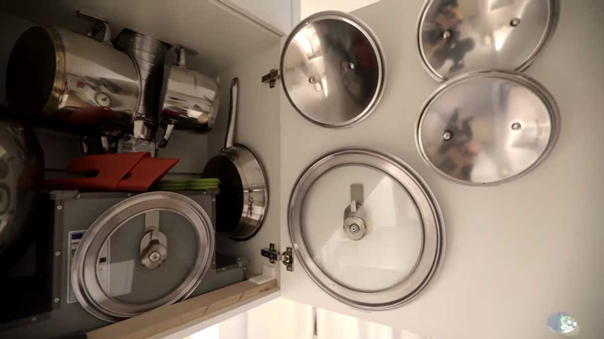 Vnitřek kuchyňské skříňky s promyšleným uložením hrnců, poklic a kuchyňských nástrojů.