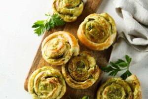 Špenátové šneky z listového těsta se sýrem podávané na dřevěném prkénku