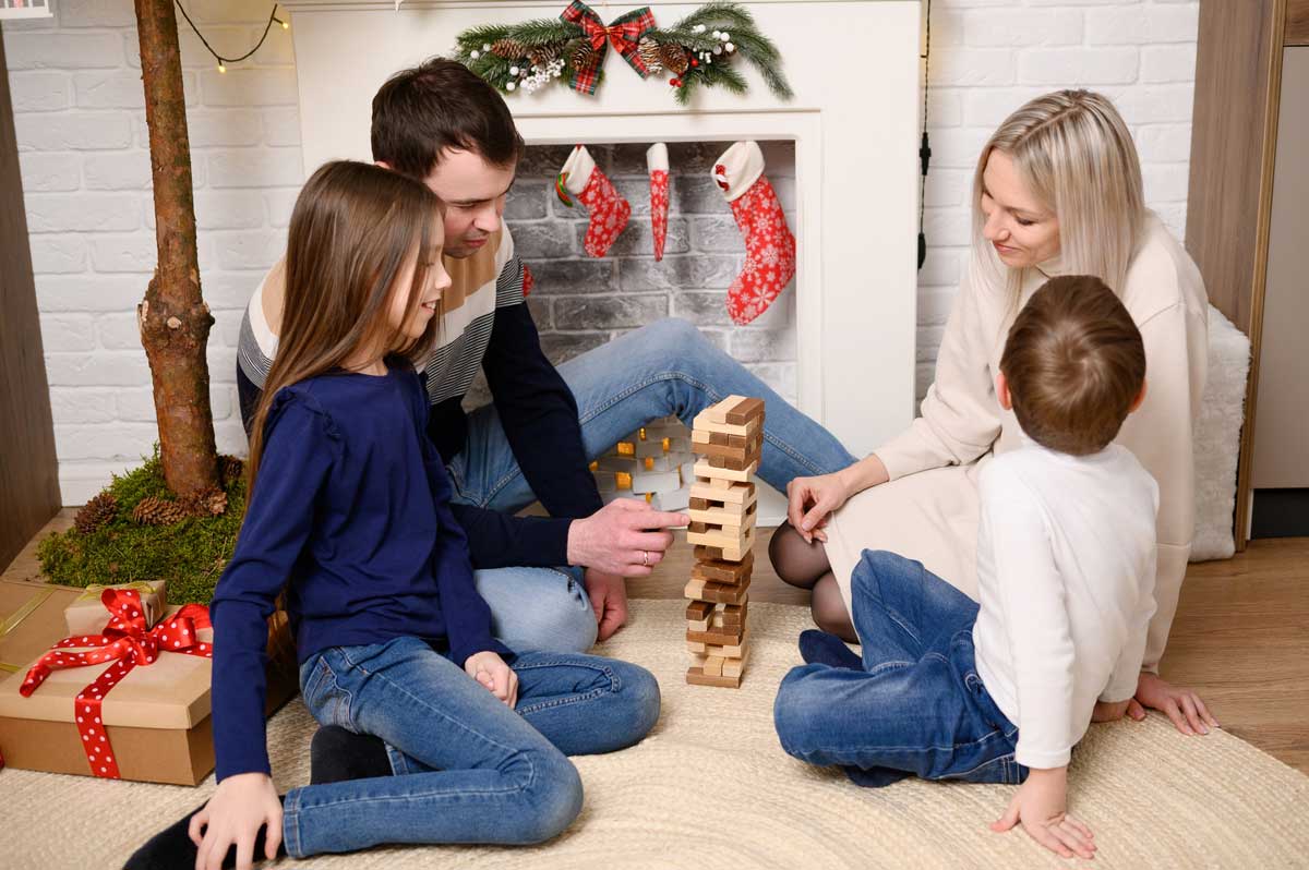 Rodina s dětmi hraje společenskou hru doma u krbu