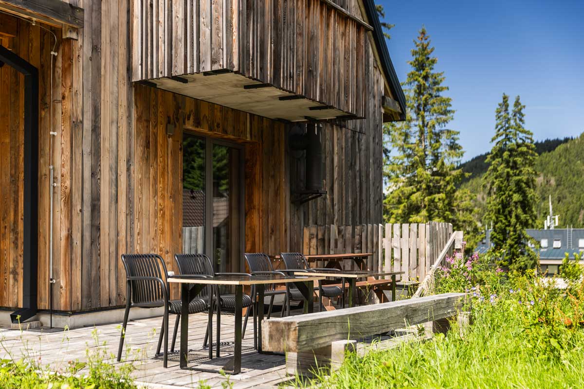 Dřevěná terasa horské chaty s venkovním posezením a výhledem do zeleně