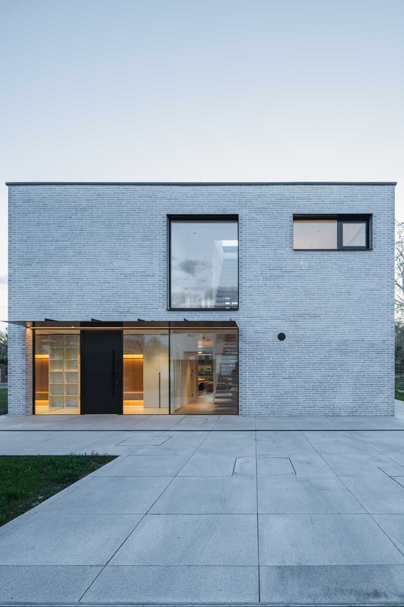 Pohled na fasádu domu s velkými okny a zastřešeným vstupem na terasu.