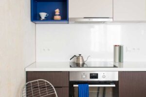 Kompaktní kuchyňská linka s integrovanou troubou a indukční deskou v malém bytě.