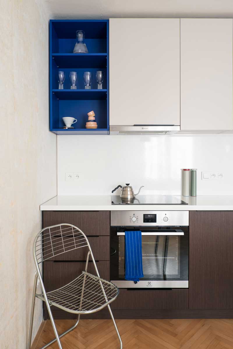 Kompaktní kuchyňská linka s integrovanou troubou a indukční deskou v malém bytě.