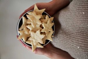 Miska světlého máslového cukroví ve tvaru hvězdiček, držená v dlaních.