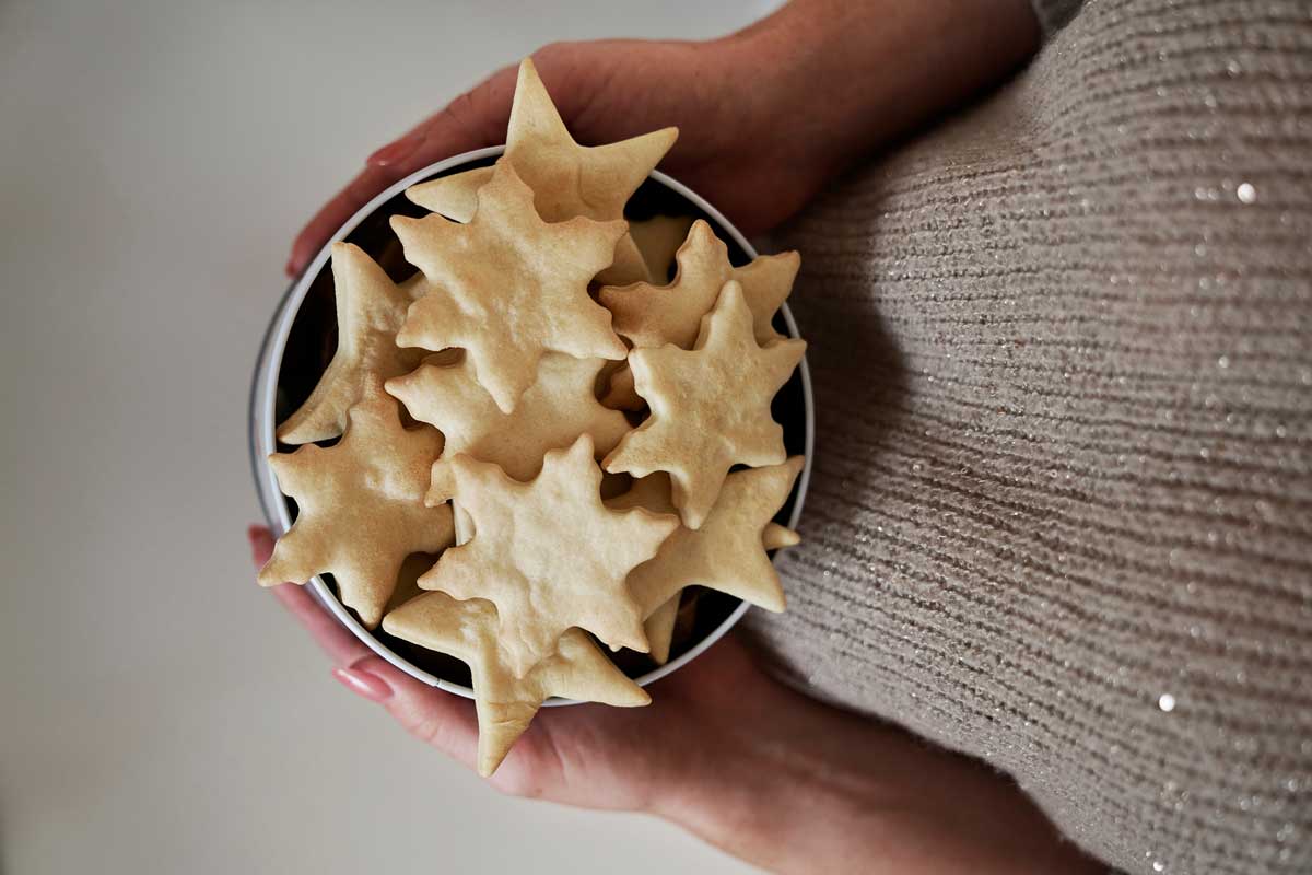 Miska světlého máslového cukroví ve tvaru hvězdiček, držená v dlaních.