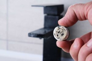 Silně zanesený perlátor vodního kohoutku, typický příklad zimního zrychleného usazování minerálů.