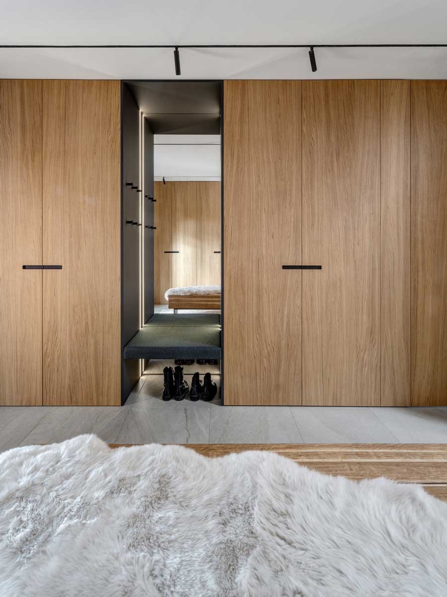 Vestavěná šatna z dubového dřeva s osvětlenou nikou a zrcadlem.