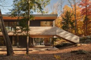 Dřevěné schodiště ve vstupní části domu s výhledem do lesa