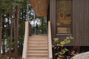 Vstup do domu s dřevěnými schody a terasou v lese