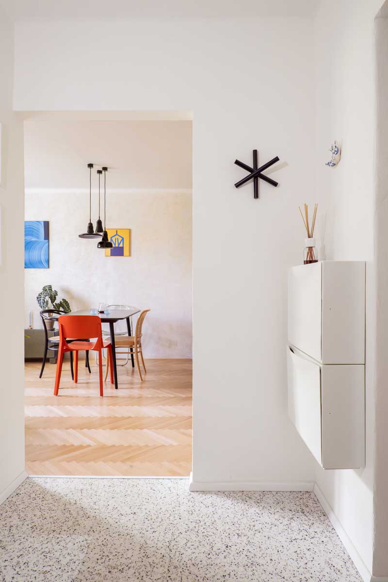 Minimalistický závěsný botník ve vstupní chodbě malého bytu.