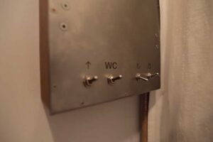 Detail kovového panelu s retro vypínači světel v garsonce.