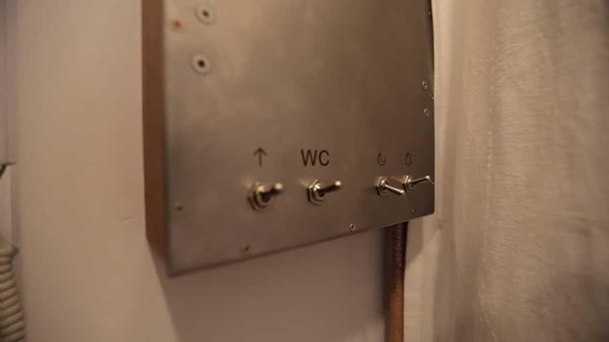 Detail kovového panelu s retro vypínači světel v garsonce.